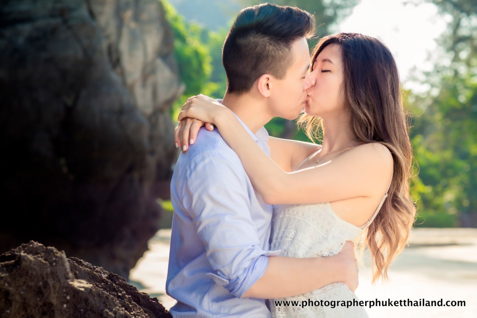 A couple kissing passionately in an outdoor setting, surrounded by nature.