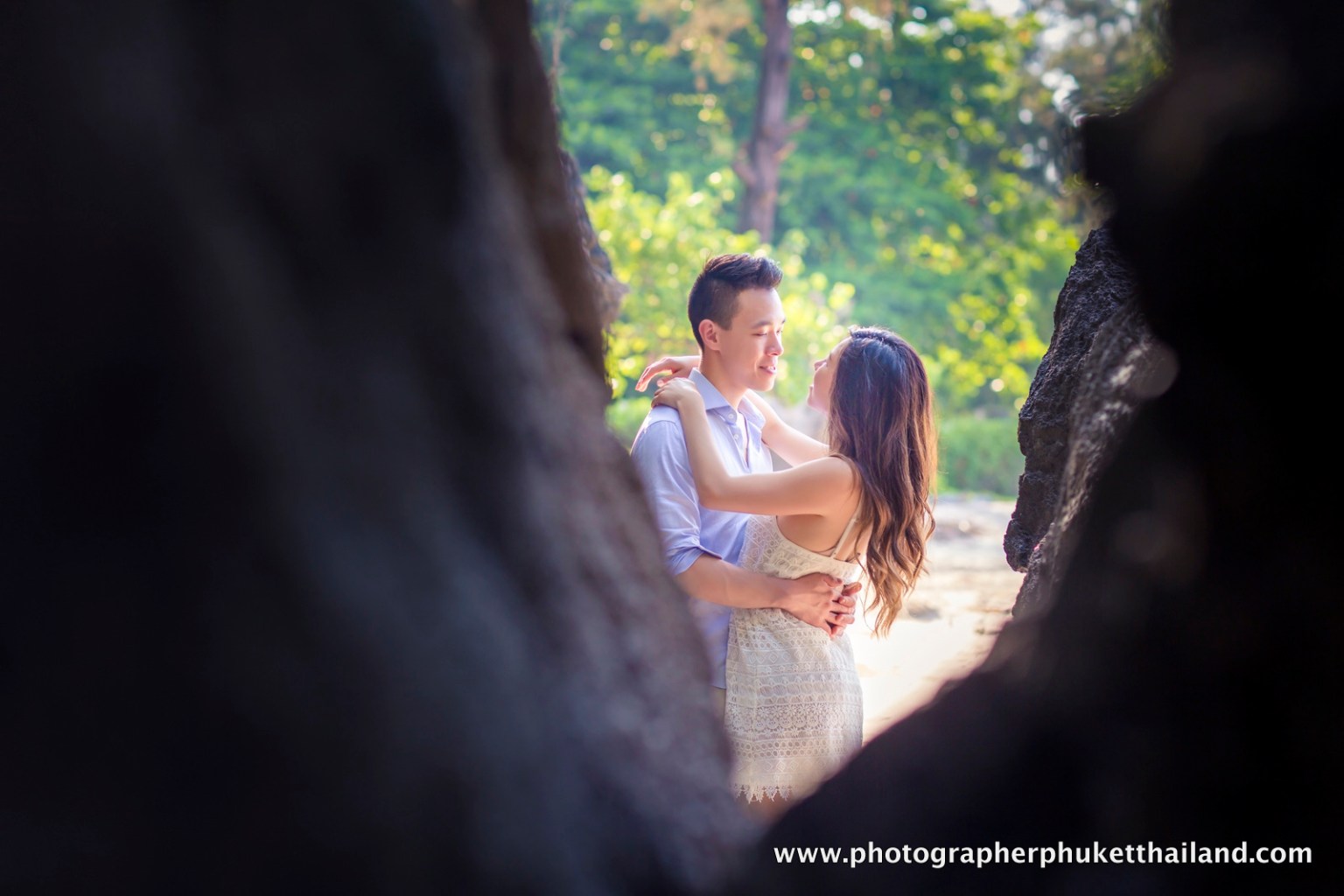 A couple embraces in a romantic setting amidst lush greenery, captured during a honeymoon photoshoot in Krabi, Thailand.