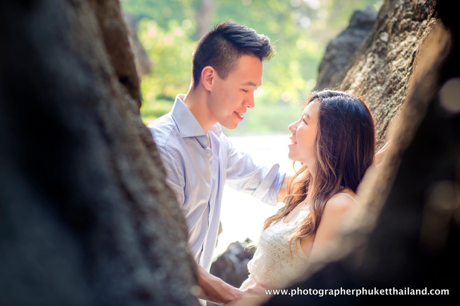 A couple enjoying a romantic moment together on a beach in Krabi, surrounded by natural rock formations and lush greenery in the background.