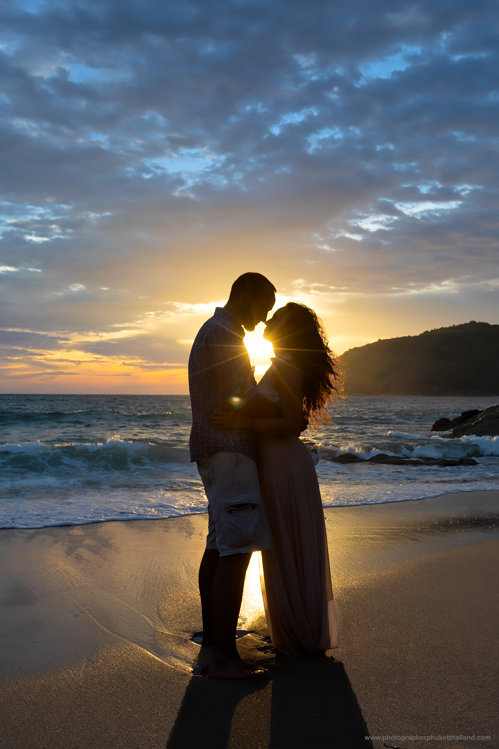 Silhouette of a couple embracing on the ya nui beach at sunset, with waves crashing in the background.