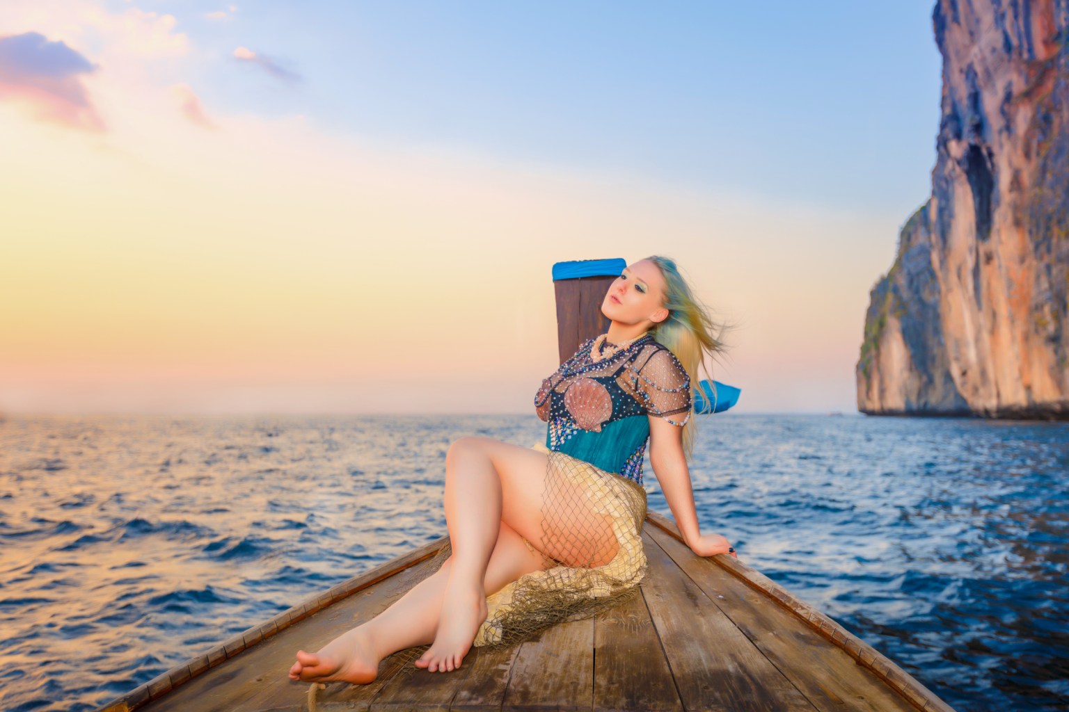 A model posing gracefully on a boat, wearing a unique outfit with seashell details, set against a serene ocean backdrop and a colorful sunset.