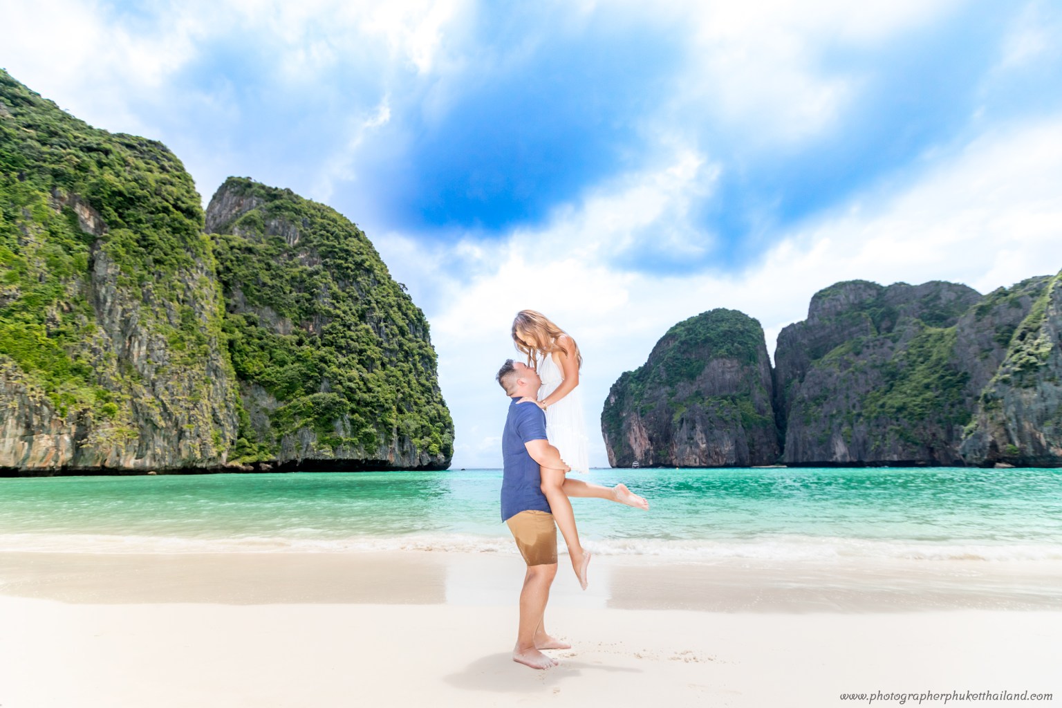 A couple posing on the beach at Maya Bay, with stunning limestone cliffs and crystal clear water in the background.