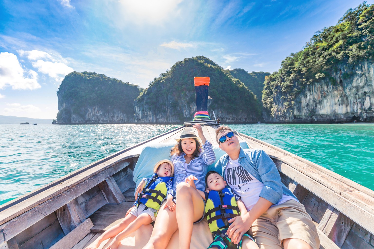 Family enjoying a boat ride in Krabi, Thailand, with limestone cliffs in the background.