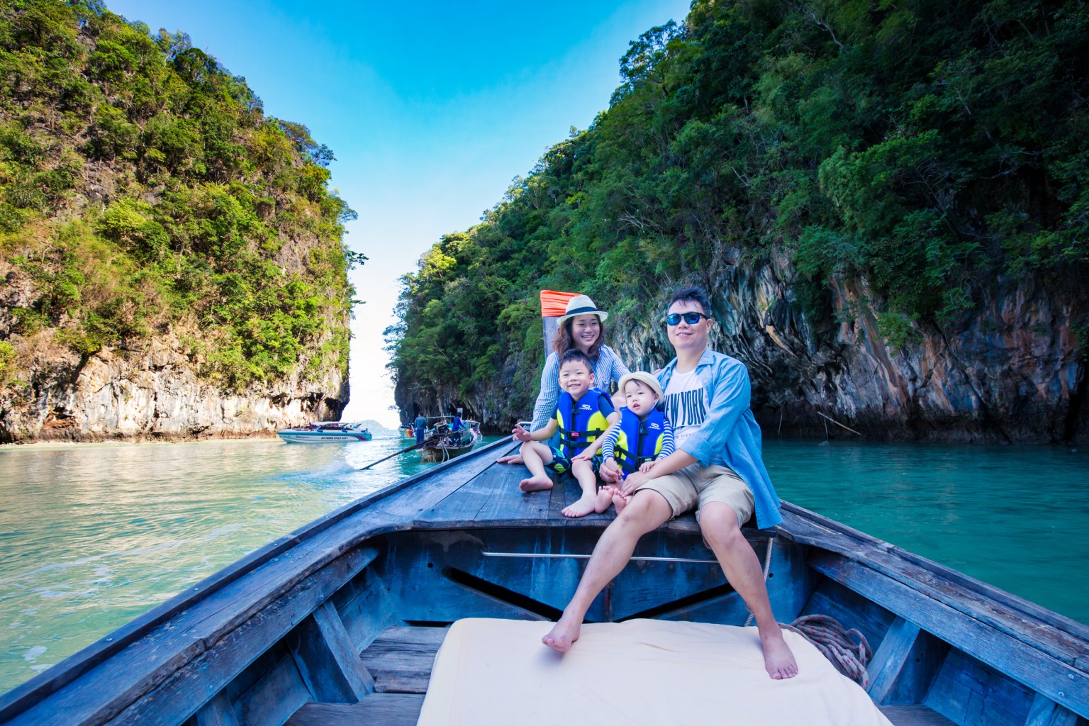 A family enjoying a boat ride in Krabi, Thailand, surrounded by limestone cliffs and clear waters.