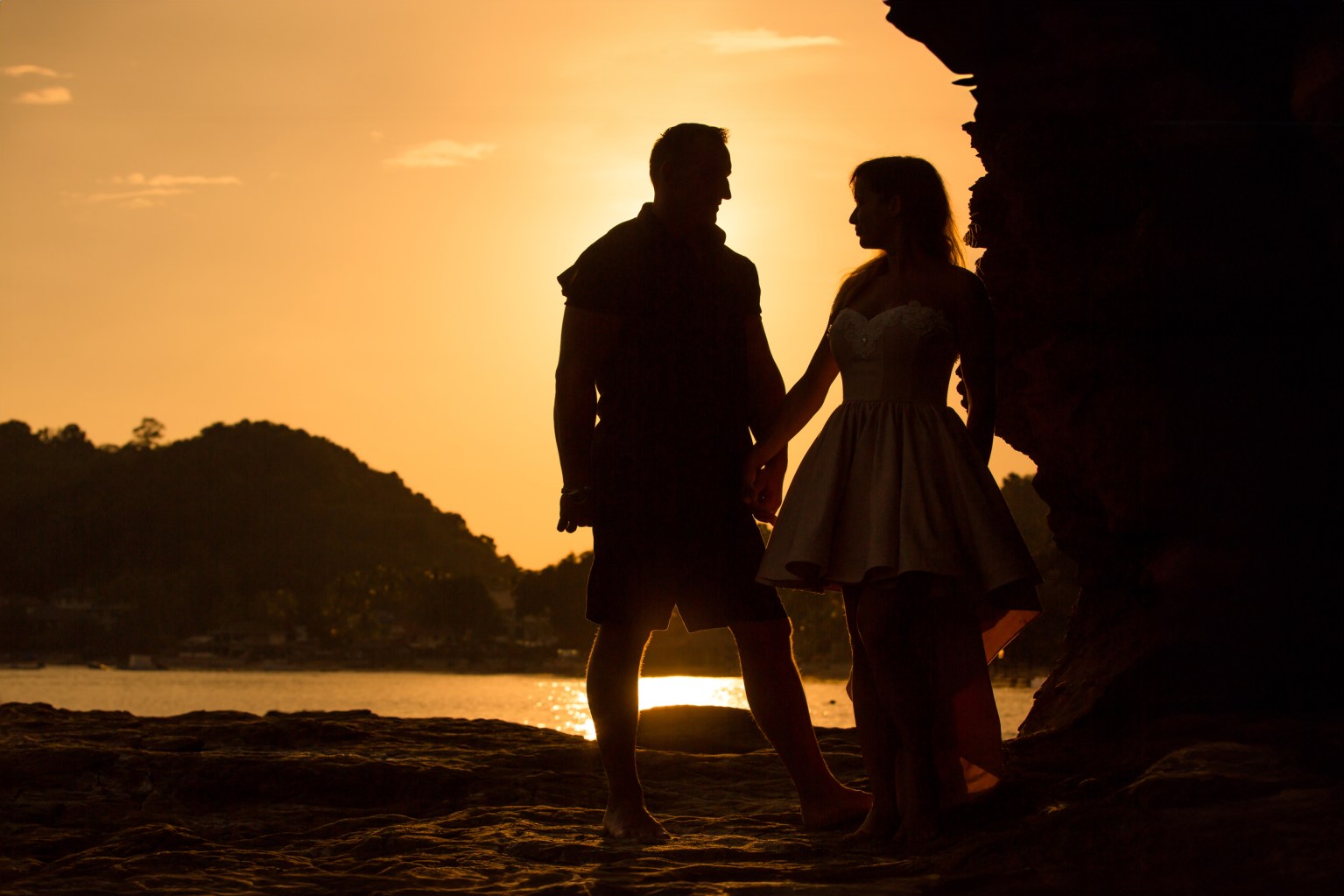 Silhouette of a couple holding hands at sunset on Ao Yon Beach in Phuket.