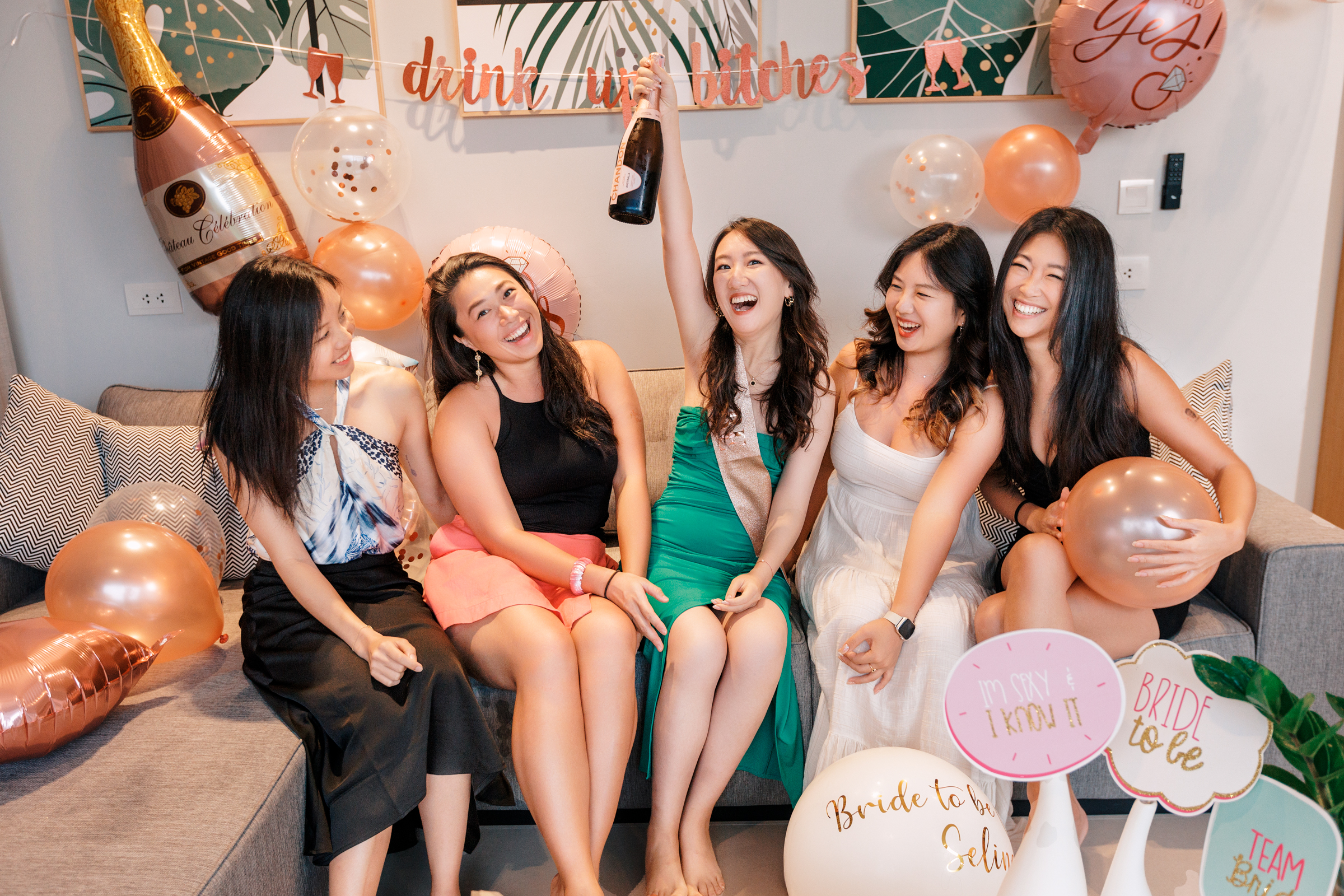Bachelor party photo shoot A group of five women enjoying a celebration, posing joyfully with balloons and decorations in a stylish indoor setting.