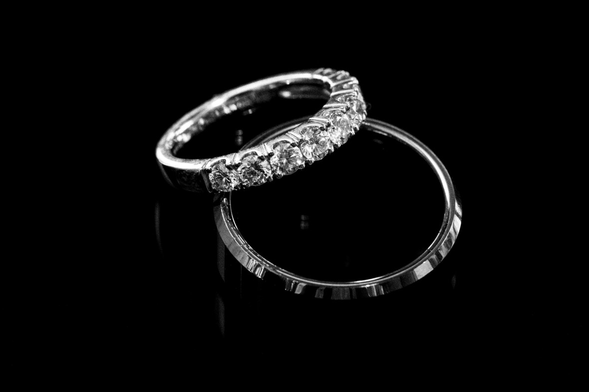 Two wedding rings displayed on a black background, showcasing their intricate details and shine.