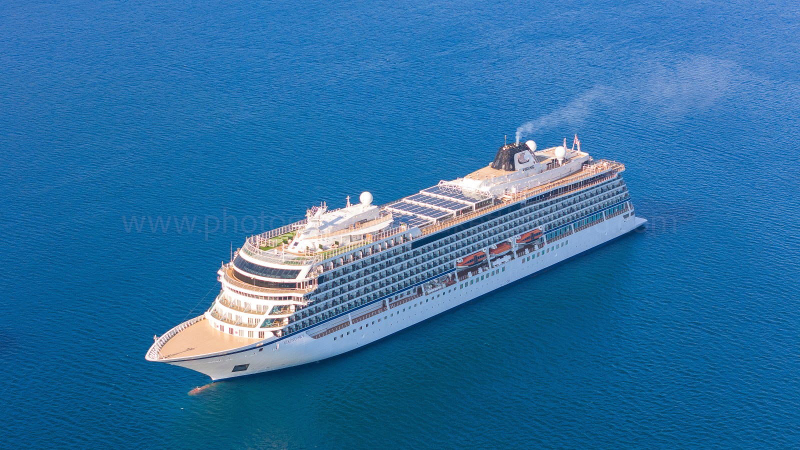 Aerial view of a large cruise ship sailing on calm blue waters.