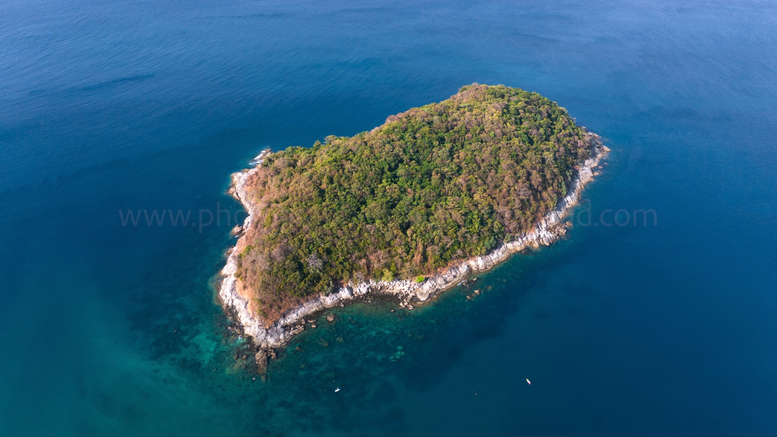 Aerial view of a small island surrounded by clear blue waters.