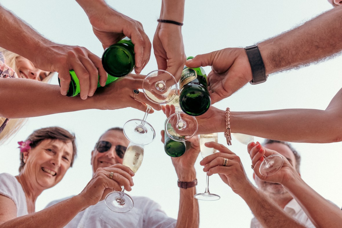 A group of people celebrating with raised glasses and beer bottles, smiling and enjoying the moment.