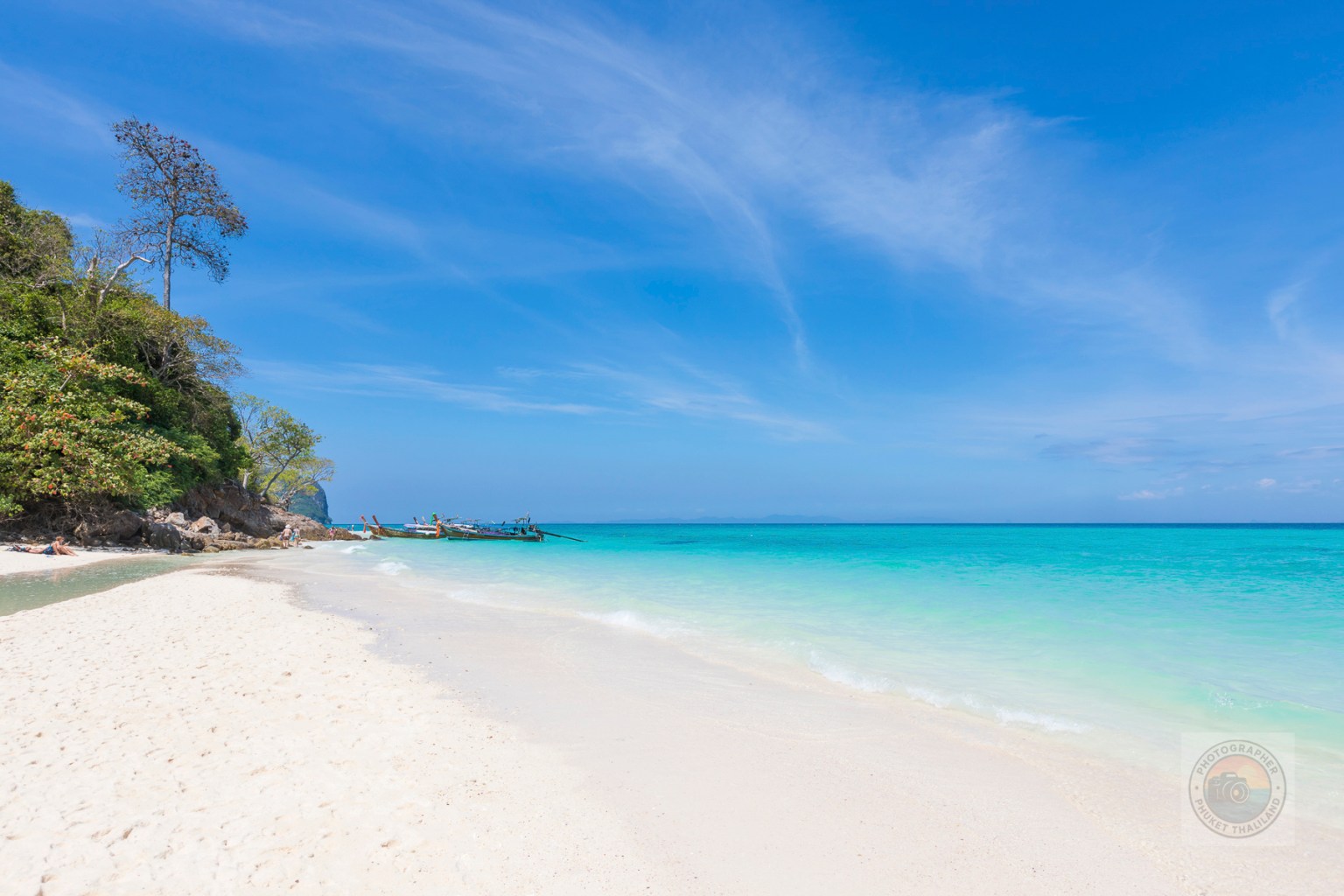 A serene beach scene at Bamboo Island, Krabi, featuring soft white sand and clear turquoise waters under a blue sky.